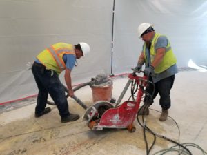 Workmen using heavy-duty saws to cut a slab of concrete