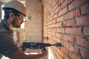 Man at a construction site in the process of drilling a wall