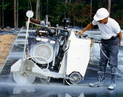 Worker using a big saw to cut through concrete