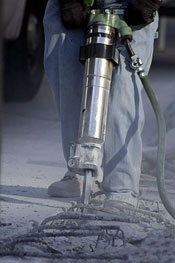 Worker using a drill to break up a concrete floor