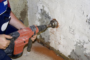 Detail shot of industrial concrete drill being used to cut into concrete wall for removal